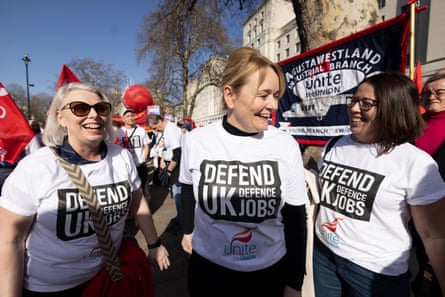 Sharon Graham with two union members at a rally in London. All three women wear T-shirts with the slogan Defend UK Defence Jobs. Graham is in her mid-50s with long blond hair tied back from her face.