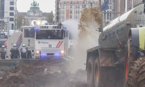 Belgian farmers spray manure towards police who respond with water cannon – video