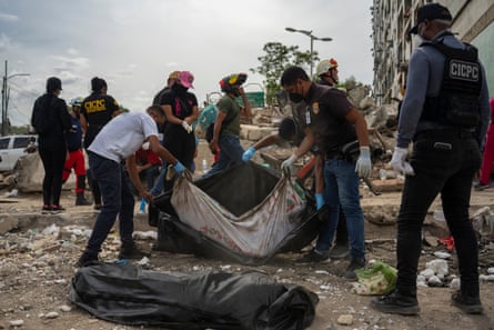 Police carry a body bag outside a building