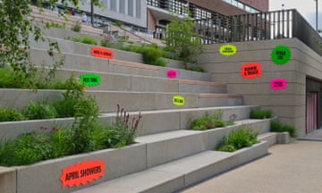 Fluorescent signs in orange, yellow, pink and green displayed on concrete steps with phrases including 'April showers', 'cream crackered', 'horse n carriage' and 'dog & bone'