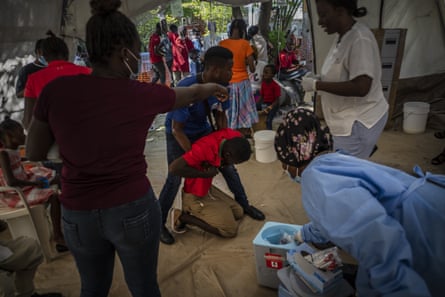 A young man displaying cholera symptoms is helped at a clinic