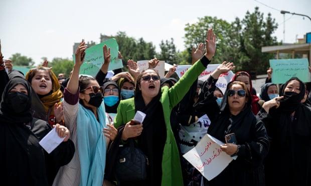 Women with handwritten placards shouting and raising their arms.