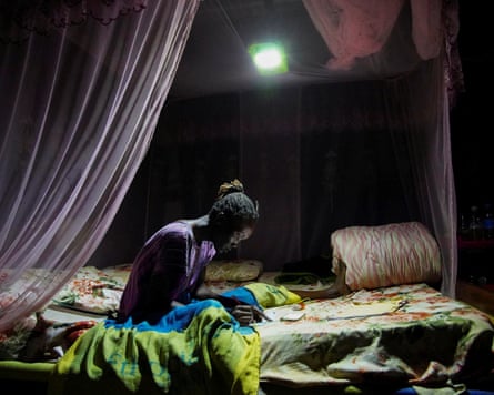 A South Sudanese girl uses a solar light to study after electricity rationing.