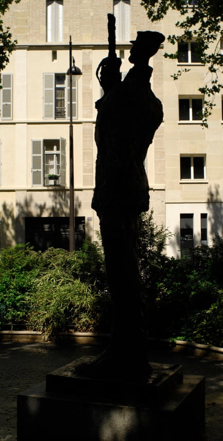 A silhouette of the Dreyfus statue in a small public garden