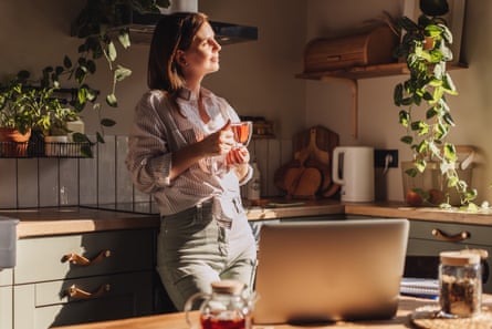 Posed by model Young happy woman drinking coffee on the kitchen in the morning.