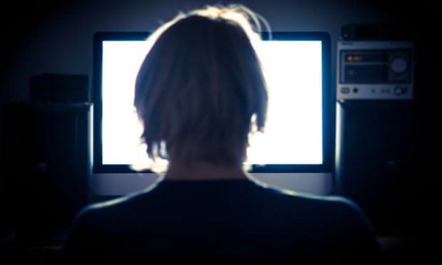 Man staring at computer screen in darkened room