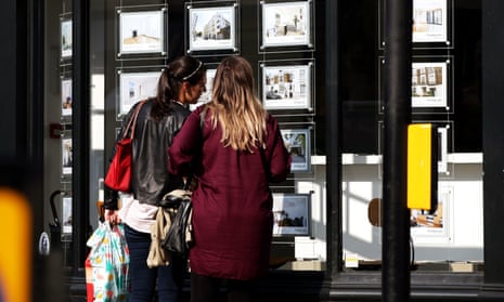 Two women looking at an estate agent's window.