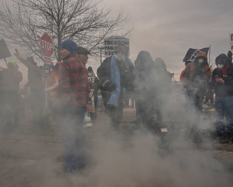 Protesters take cover as teargas is deployed by federal immigration officers outside Bishop Henry Whipple Federal Building in Minneapolis, 15 January 2026.