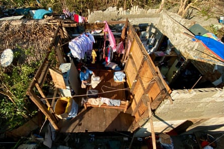 A villager arranges her belongings at a house with a blown-off roof in the typhoon-hit town of Claveria, Cagayan province