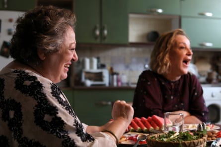 Two woman at a kitchen table with food on