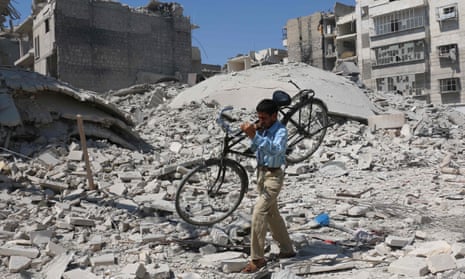 A Syrian man carries a bicycle through rubble