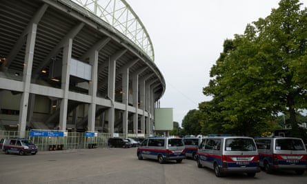 A number of police vehicles parked outside as the stadium towers above them