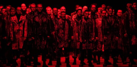 A group of performers on stage, bathed in red lighting, in Jocasta’s Line.
