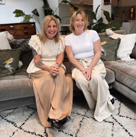 Amanda Stanhope, left, and Zoe Watts, laugh as they sit in a living room.