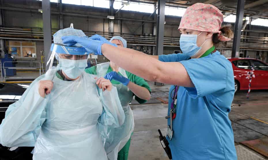 Medical staff put on their personal protective equipment (PPE) at a testing centre in Belfast, Northern Ireland.