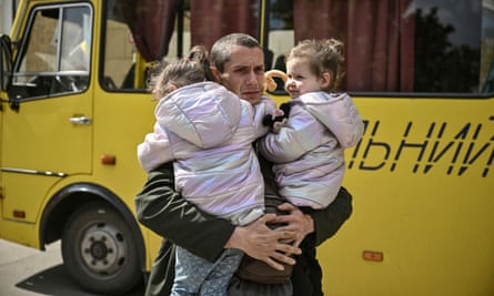 Dmytro Mosur, 32, who lost his wife during shelling in Sievierodonetsk on 17 May, holds his two-year-old twin daughters as they wait to be evacuated.