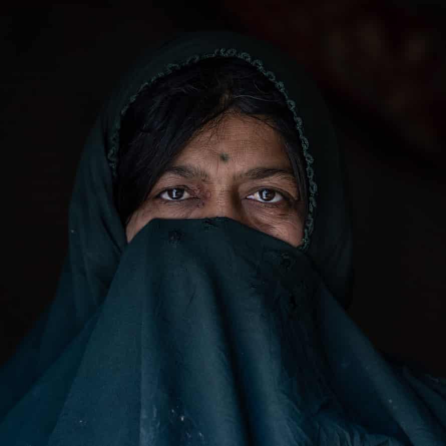 A woman looks at the camera while covering most of her face with her veil 