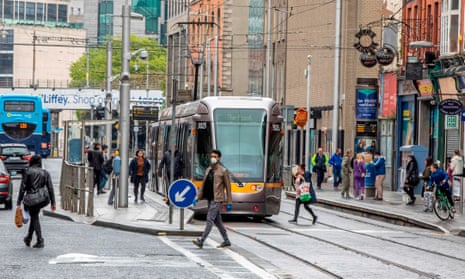 Pedestrians cross tram tracks on a street in central Dublin