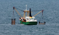 A trawler lowers its nets to catch demersal fish