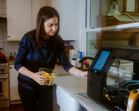 She puts potatoes into a black cooking appliance on the countertop