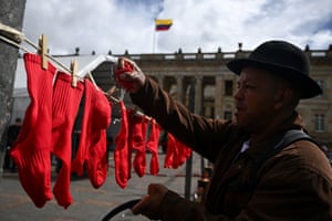 A man hangs red socks on a line in a public place