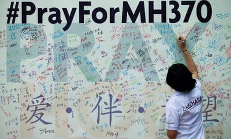 A woman writes a message on a board in Kuala Lumpur soon after the plane’s disappearance