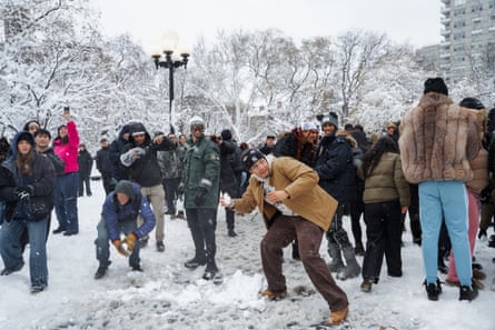 Young people duck as they throw snowballs at each other in a park