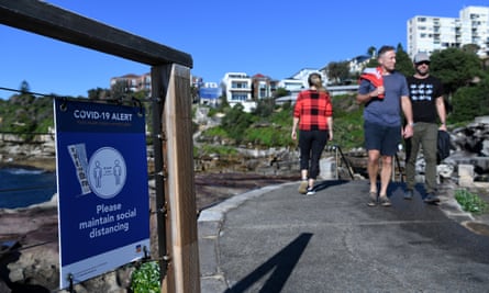 A social distancing sign sits on the fence along the walking path from Bondi to Bronte.
