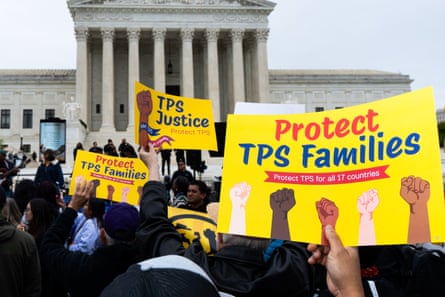 people hold signs that read ‘protect tps families’