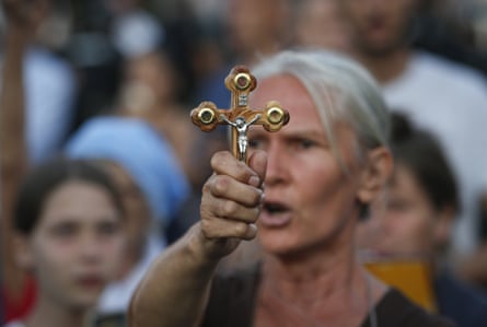 Woman in crowd holding up crucifix.