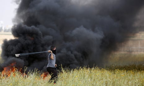 A Palestinian slings stones towards Israeli soldiers during clashes along the border with Israel.