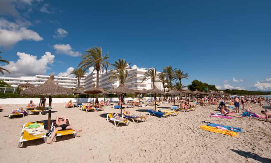People enjoy the sun on a beach in Mallorca