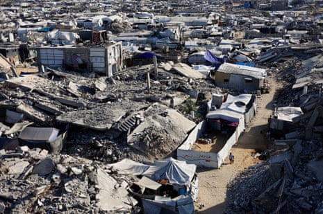 Palestinian children walk past the rubble of residential buildings destroyed during the war.