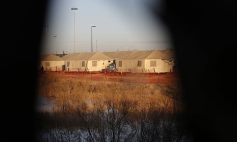 Tents are seen through a hole in the tarp that covers the fence of the Tornillo detention camp, in December.