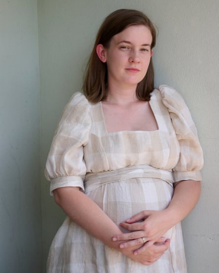 Maddy Hoffman is a Perth PhD student who has had to rely on her partner's income to get her over the line. She is wearing a neutral-coloured dress and standing in front of a blank wall