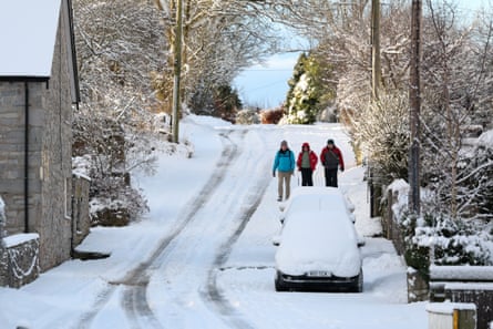 People walk down a snow-covered hill in Mold, Wales