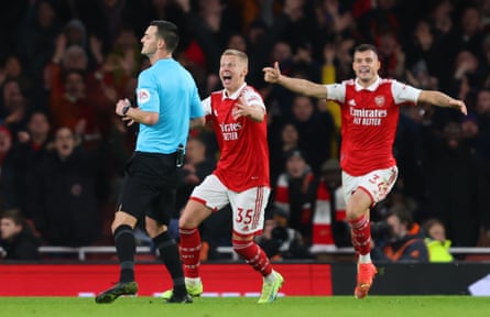Oleksandr Zinchenko and Granit Xhaka pursue Andy Madley in hopes of getting a penalty call.