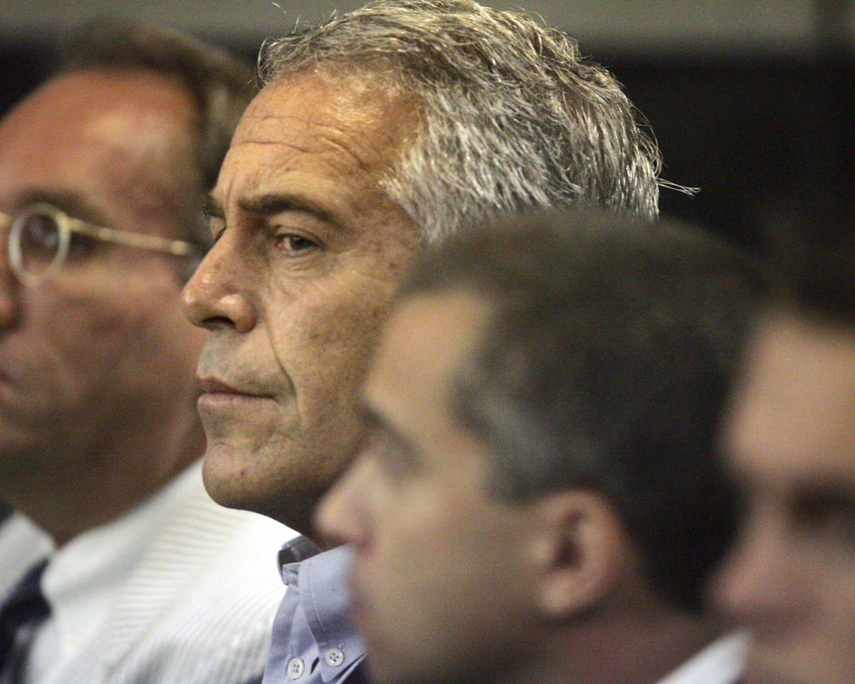Jeffrey Epstein sits in profile in a courtroom, with blurred figures beside him