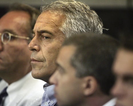 Jeffrey Epstein sits in profile in a courtroom, with blurred figures beside him