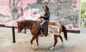 Brianna Noble rides her horse Dapper Dan through downtown Oakland last Friday.