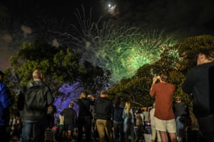 People watch the early family fireworks from the Sydney Botanic Garden