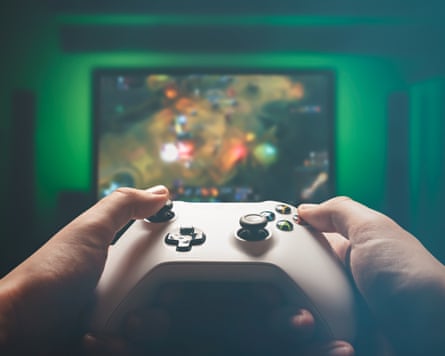 A man, holding a console controller, is playing an RPG strategy game on a green backlit TV