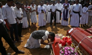 People gather at a mass burial of victims at a cemetery near St Sebastian church in Negombo, Sri Lanka
