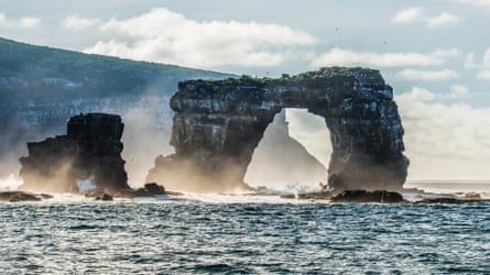Landscape view of Darwin’s Arch, Galápagos, with the sea crashing around its base