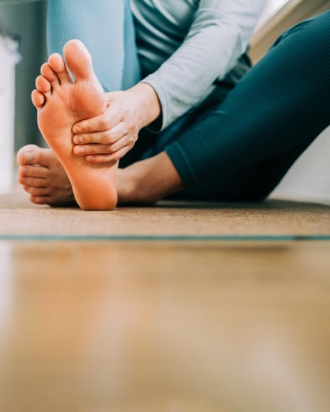 Woman massages her feet on yoga mat