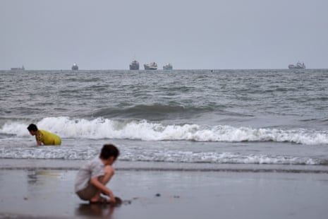 Children play at a beach as commercial vessels are anchored in the strait of Hormuz off Bandar Abbas in Iran.