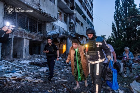A rescuer assists a woman during an evacuation from apartment building damaged by a Russian drone strike, amid Russia's attack on Ukraine, in Kharkiv, Ukraine.