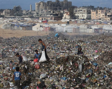 Displaced Palestinian children search through rubbish next to destroyed buildings in Gaza