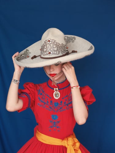 A woman in Mexican escaramuza dress in a red dress and cowboy style hat