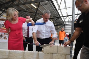 Bill Shorten’s wife, Chloe, moves his tie as he lays a brick during a visit to a Tafe campus in Perth